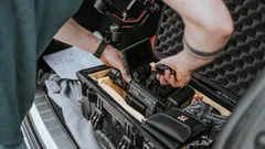 Persona con botas negras preparando equipo RED Scarlet W en asiento de auto