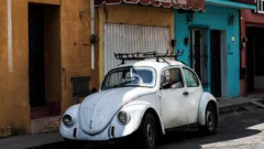 Volkswagen Beetle blanco estacionado junto a edificio de concreto marrón