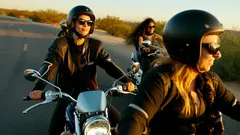 Mujeres conduciendo motocicletas en carretera al atardecer