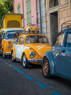 Volkswagen Beetle amarillo estacionado en la calle junto a otros autos